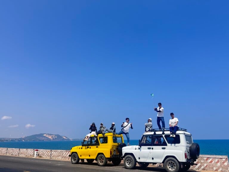 旅客与黄白色吉普车在美奈海岸公路合影